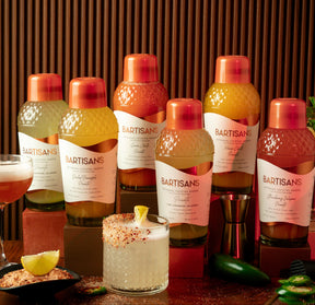 Bartisans bottles on a wooden table with picante cocktails and ingredients