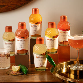 Bartisans picante flavoured drinks with a cocktail and garnish on a wooden surface.